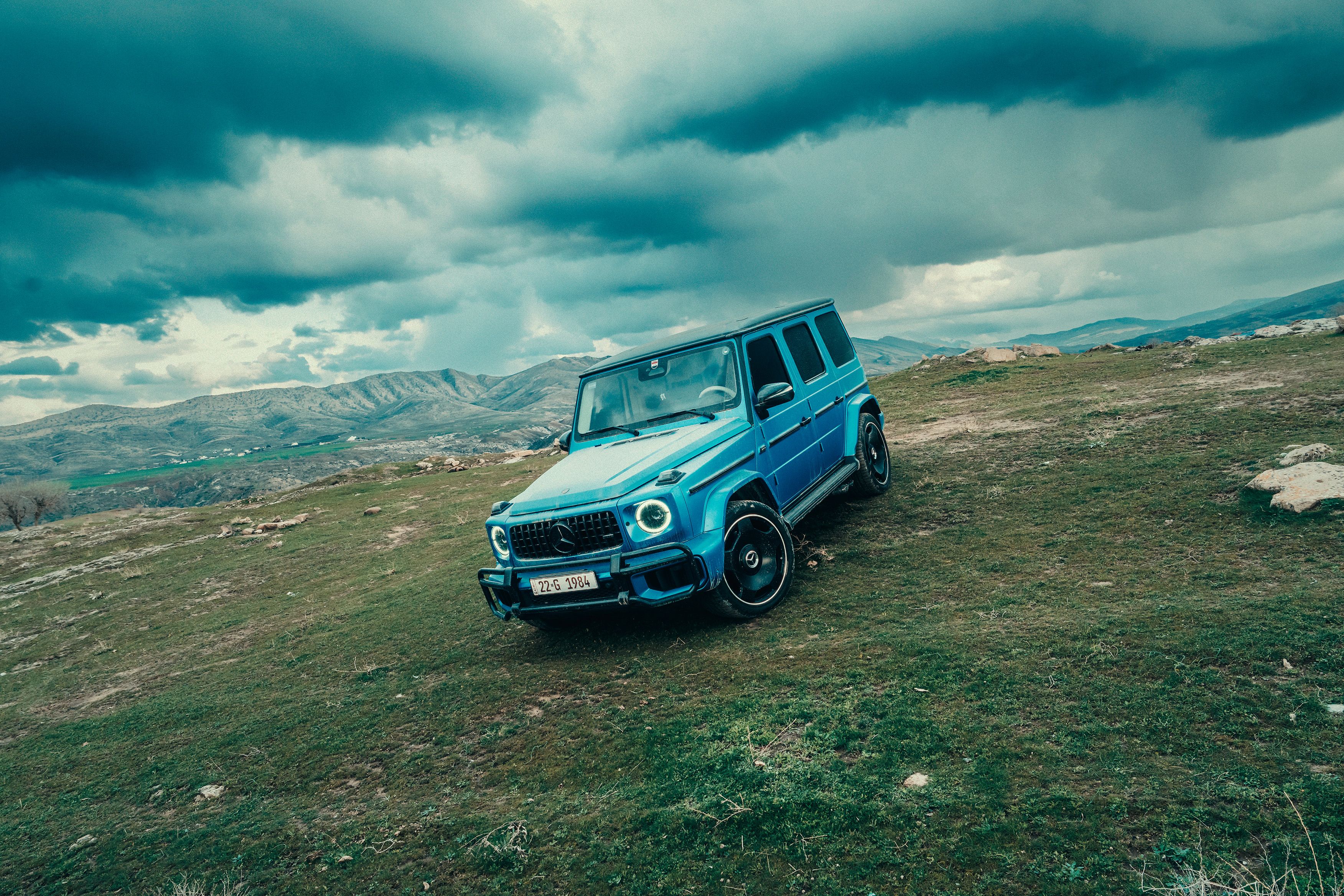 Luxury Mercedes G-Class SUV parked on rugged mountain terrain.